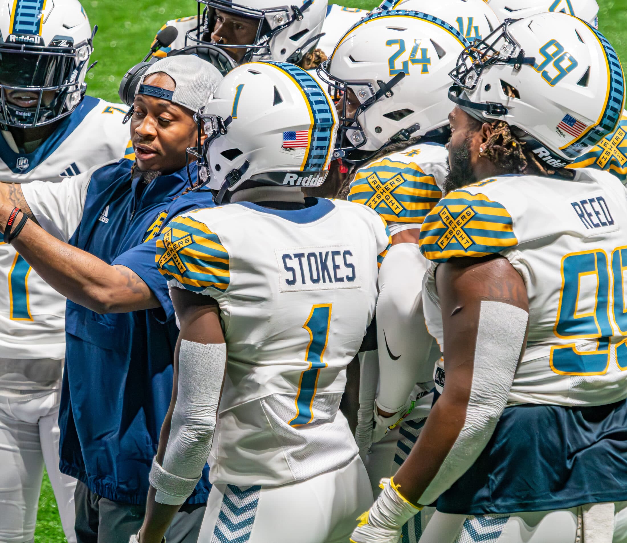Coach K on the sideline reviewing a play with his athletes